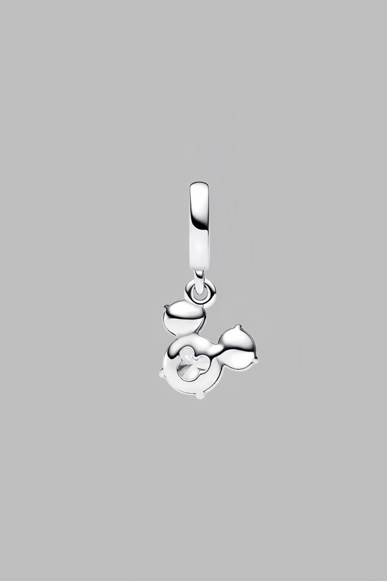 May include: A silver charm pendant in the shape of Mickey Mouse. The charm has a loop at the top for hanging and features Mickey's iconic silhouette with a cut-out design. The charm is made of shiny, polished metal.