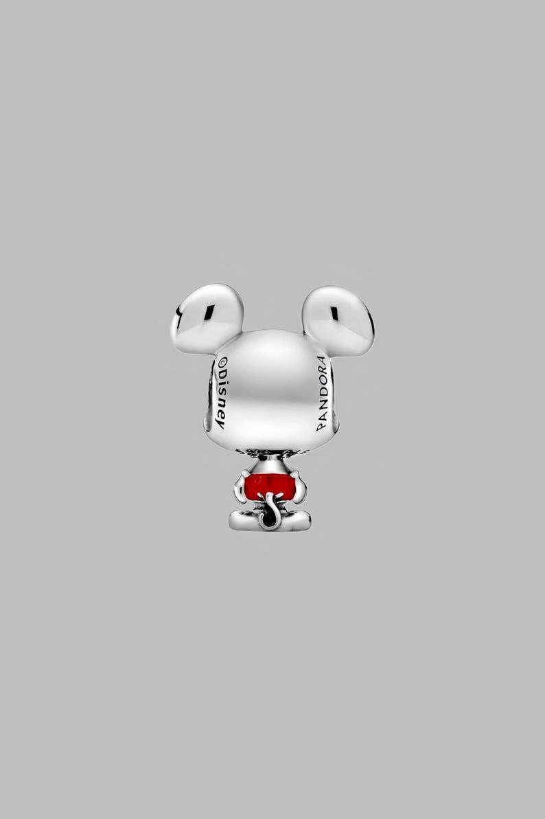 Peut inclure: Un charm en argent repr&eacute;sentant Mickey Mouse. Le charm pr&eacute;sente les oreilles embl&eacute;matiques de Mickey et une partie rouge &agrave; la base. Le mot "Disney" est inscrit sur le c&ocirc;t&eacute;. Le mot "Pandora" est &eacute;galement inscrit sur le c&ocirc;t&eacute;.