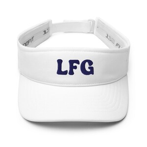 May include: White visor with navy blue embroidered letters spelling "LFG". The visor features an adjustable strap and a curved peak. The text is positioned centrally on the front.