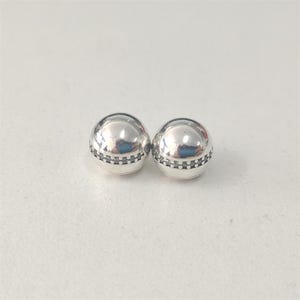 Könnte beinhalten: Zwei silberfarbene, kugelförmige Perlen. Jede Perle hat ein Band aus kleinen, dunkel gefärbten Steinen um die Mitte. Die Perlen sind hochreflektierend, mit einer glatten, polierten Oberfläche. Schmuck.