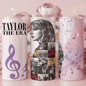 May include: Three cylindrical tumblers featuring a light pink background with purple musical notes. One tumbler displays the text TAYLOR THE ERAS, while another showcases a collage of black and white photographs of a person performing on stage.