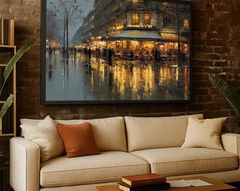 May include: A framed art print depicting a rainy street scene in a European city at night. The artwork features a restaurant with outdoor seating, illuminated by warm lights, and reflections on the wet pavement. The print is displayed above a beige sofa.