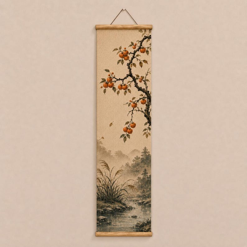 May include: A vertical wall hanging scroll featuring a painting of a tree branch with orange fruit extending over a landscape. The scene depicts a stream flowing through a misty forest with tall grasses in the foreground, all on a textured beige fabric.