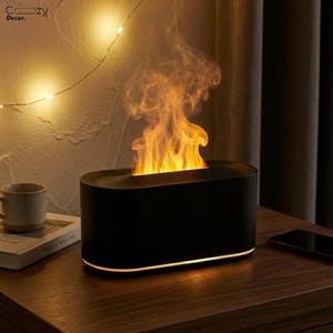 Peut inclure: Lampe décorative noire de forme ovale avec un effet de flamme. La lampe émet une lueur orange chaude par le haut, simulant un feu. La base a une lumière orange douce. La lampe est posée sur une surface en bois.