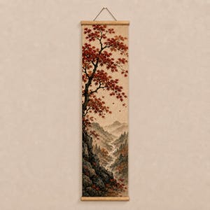 May include: A vertical wall hanging scroll featuring a detailed landscape painting. The artwork depicts a rocky cliffside with a large tree displaying vibrant red autumn leaves, overlooking a misty valley with distant mountains and a winding stream.