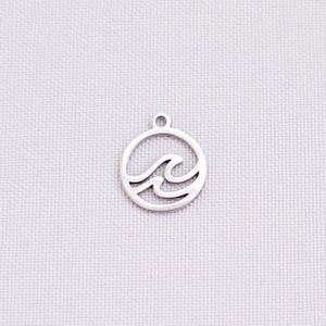 May include: A silver-colored charm featuring a wave design within a circular frame. The charm has a small loop at the top for attaching to jewelry. The wave design is a simple, elegant representation of ocean waves.