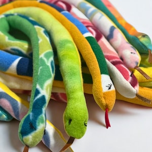 May include: A collection of colorful plush snake toys. The snakes are made of soft fabric in various patterns and colors, including green, blue, yellow, and pink. Each snake has a detailed head with eyes and a tongue. The toys are designed for children.