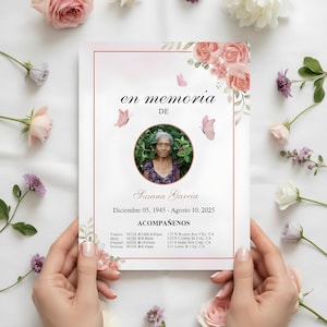 以下が含まれることがあります： 手で持たれた追悼カード。Susana Garciaの肖像画が特徴です。カードはピンク色の縁取りと花のアクセントがあり、スペイン語で日付と「en memoria」というフレーズが含まれています。ピンク色の蝶と花がカードを囲んでいます。