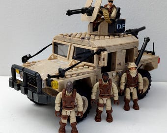 May include: A tan camouflage military vehicle constructed from building blocks, featuring a roof-mounted turret with a black machine gun and a soldier figure. Three additional soldier figures stand in front, wearing tactical gear and masks.