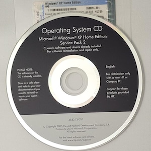 Può includere: Un CD del sistema operativo Microsoft Windows XP Home Edition Service Pack 2 per computer HP e Compaq. Il disco presenta testo nero e argento, incluse informazioni sul copyright e istruzioni per la reinstallazione del software.