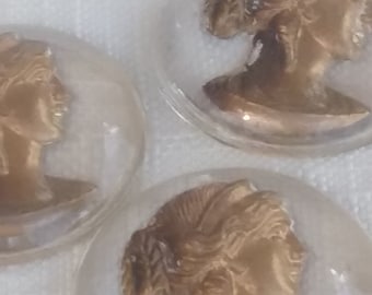 May include: Three clear glass cabochons with gold toned images of women's profiles.