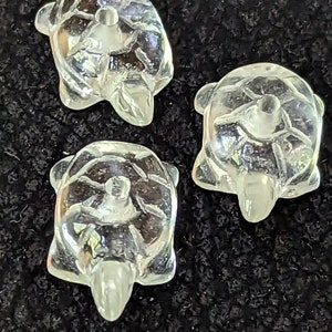 Op de afbeelding: Drie transparante glazen schildpadfiguren. De schildpadden zijn klein en gedetailleerd, met een gladde, gepolijste afwerking.