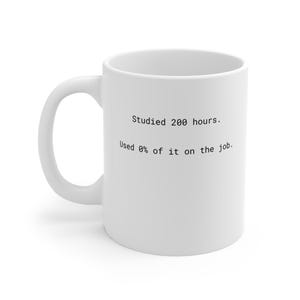 May include: White ceramic mug with a curved handle. The mug has black text that reads: "Studied 200 hours. Used 0% of it on the job."