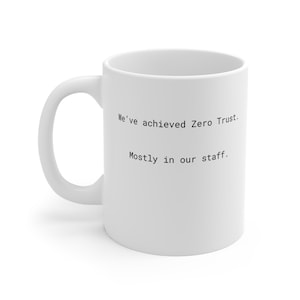 May include: White ceramic mug with a curved handle. The mug features the text "We've achieved Zero Trust. Mostly in our staff." printed in black. Suitable for hot or cold drinks, this mug is a humorous gift.