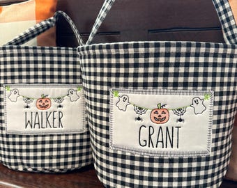 May include: Two black and white checkered Halloween trick-or-treat bags with embroidered ghosts, pumpkins, and spiders. The bags have the names "Walker" and "Grant" embroidered on them.
