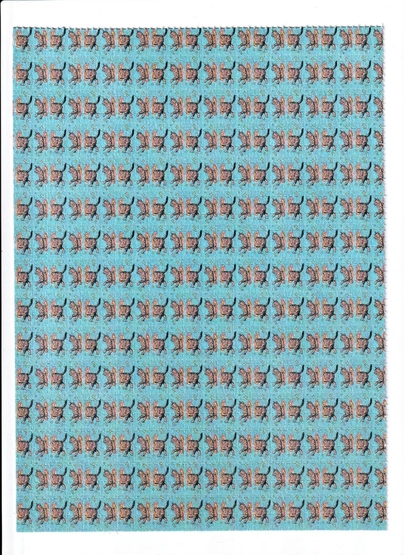 May include: A sheet of paper with a repeating pattern of brown and black cat illustrations on a light blue background. The cats are depicted in a running pose, creating a playful and whimsical design.