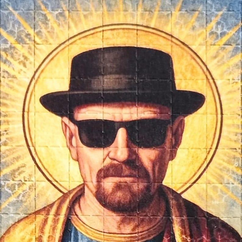 May include: A portrait of a man wearing a black fedora and sunglasses, with a halo effect. The image has a religious art style, with a yellow and blue tiled background. The man has a beard and is wearing a gold and blue garment.