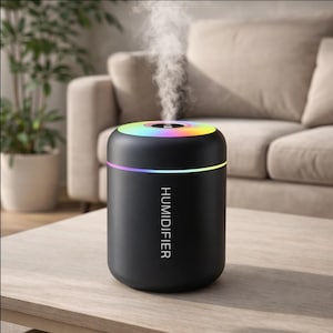 Puede incluir: Un humidificador negro con un anillo de luz multicolor en la parte superior. La palabra "HUMIDIFIER" está impresa verticalmente en el lateral. Se ve vapor saliendo de la parte superior del aparato. El humidificador está sobre una mesa de madera.