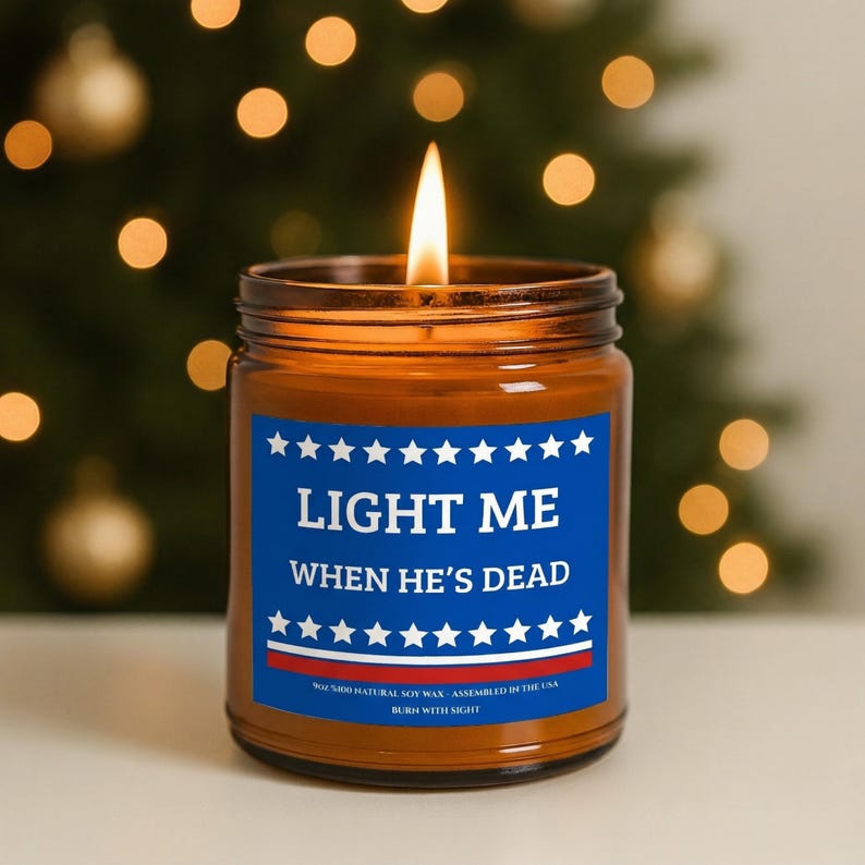 Amber glass candle jar featuring a patriotic blue and red label that says "Light Me When He's Dead" with white stars.