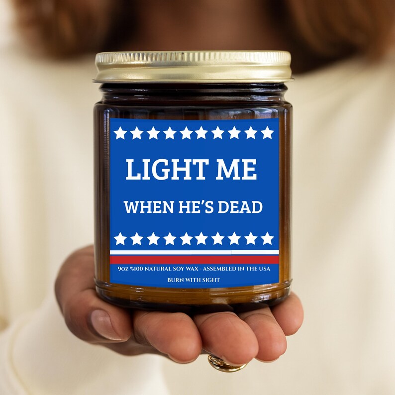 Amber glass candle jar featuring a patriotic blue and red label that says "Light Me When He's Dead" with white stars.