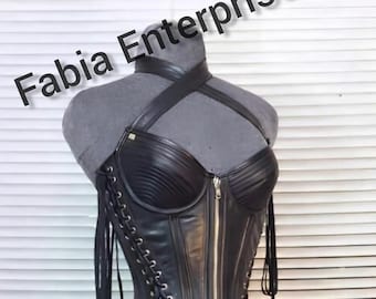 May include: Black leather corset with a halter neck and front zipper. The corset features vertical paneling and lace-up detailing on the sides. The text "Fabia Enterprises" is visible in the upper left corner.