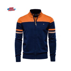 Puede incluir: Un suéter con cremallera azul marino y naranja con cuello alto. El suéter presenta rayas beige en las mangas y un pequeño logotipo cerca del pecho. La cremallera tiene un tirador decorativo. Las palabras "FREE SHIPPING" están en la esquina superior izquierda.