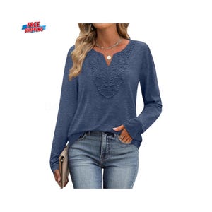 May include: A navy blue long-sleeved top with an embroidered neckline. The top has a V-neck design with detailed floral patterns. The sleeves are long and the fabric looks like a soft knit. The model is wearing blue jeans.