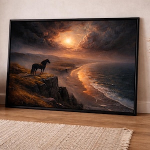 Puede incluir: Una impresión artística enmarcada muestra un caballo negro sobre un acantilado con vistas a una playa al atardecer. El cielo está lleno de nubes dramáticas y el océano refleja la luz dorada. La obra de arte se exhibe en una habitación con una cesta tejida y un jarrón.