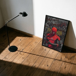 May include: A framed poster featuring Spider-Man in a red and black suit, with the word "Spider-Man" prominently displayed. The background is a collage of comic book panels. A black lamp stands nearby on a wooden floor.