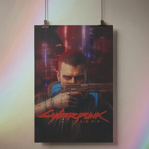 K&ouml;nnte beinhalten: Poster mit einem Mann, der eine Waffe anvisiert, mit dem roten Text "Cyberpunk 2077". Der Hintergrund zeigt eine verschwommene Stadtlandschaft mit roten und blauen Farbt&ouml;nen. Das Poster wird von zwei Clips gehalten.