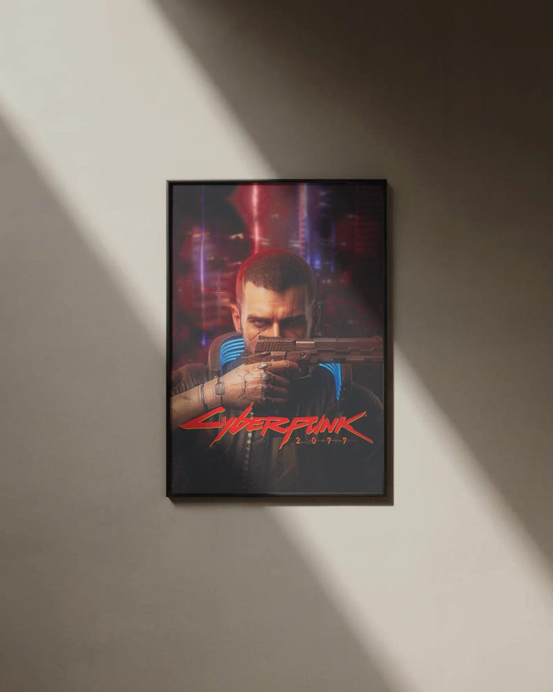 K&ouml;nnte beinhalten: Gerahmtes Poster mit einer Person, die eine Waffe h&auml;lt, und dem roten Text "Cyberpunk 2077". Der Hintergrund zeigt eine verschwommene Stadtlandschaft mit roten und violetten Farbt&ouml;nen. Das Poster ist in einem schwarzen Rahmen.