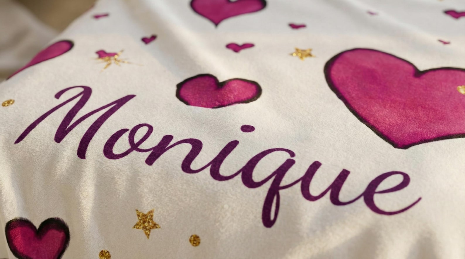 The personalized pink heart blanket styled on a bed with pillows