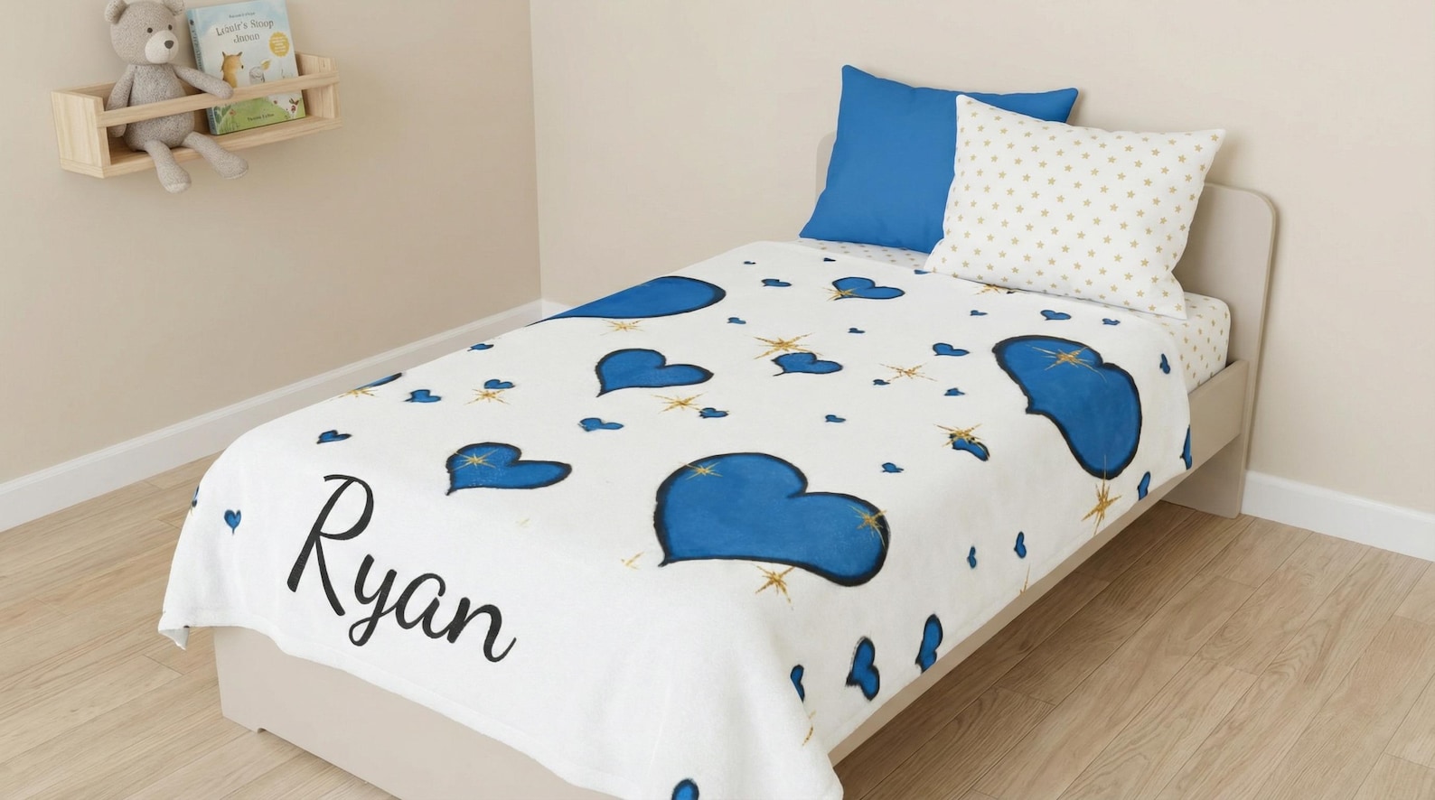 The personalized blue heart blanket laid across a child's bed with matching pillows