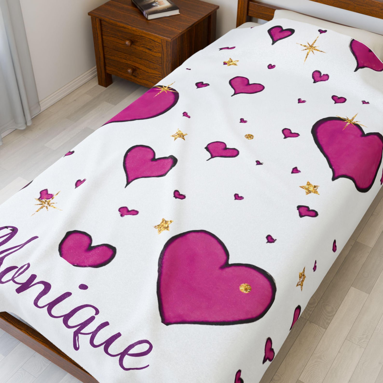 The pink heart blanket laid across a bed in a cozy bedroom setting