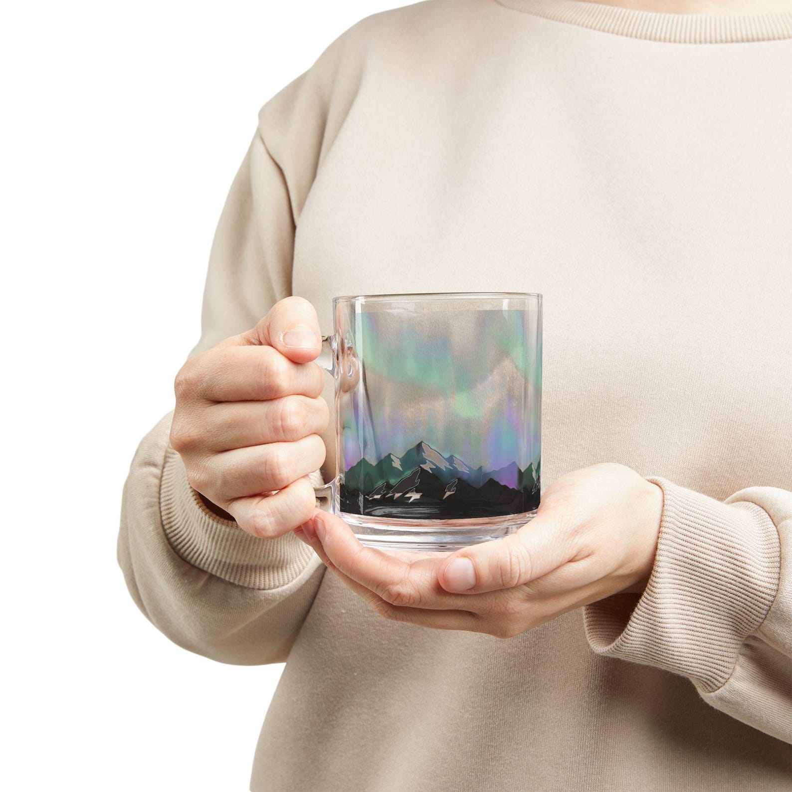 Close-up of two hands cradling the aurora borealis glass mug against a plain background