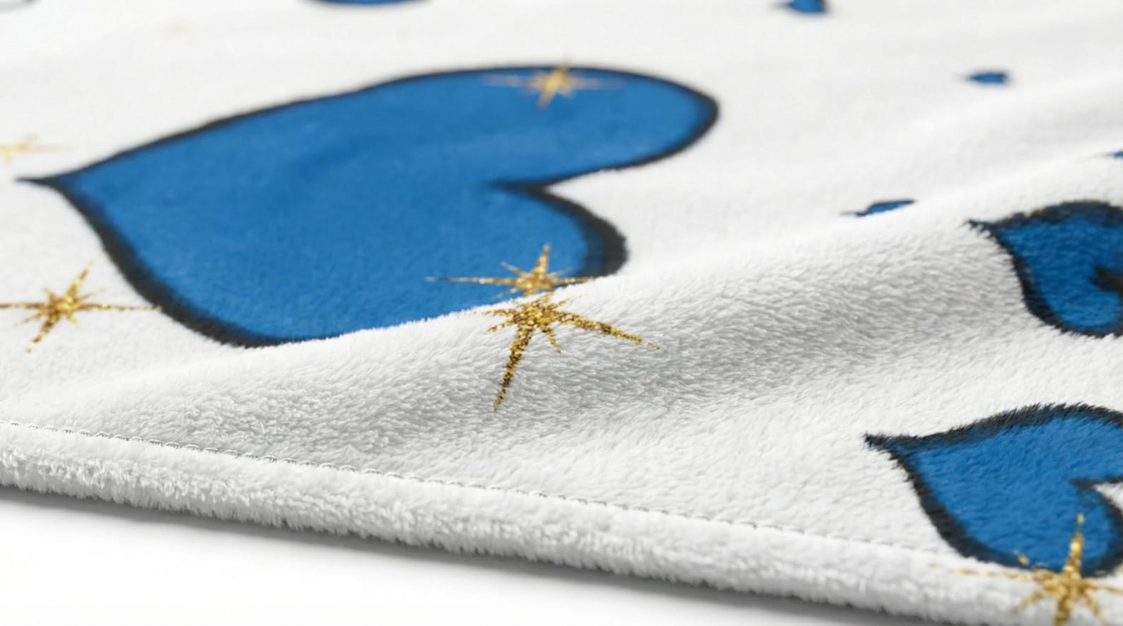 Close-up of the soft velveteen texture of the blanket, showing blue hearts and gold star accents