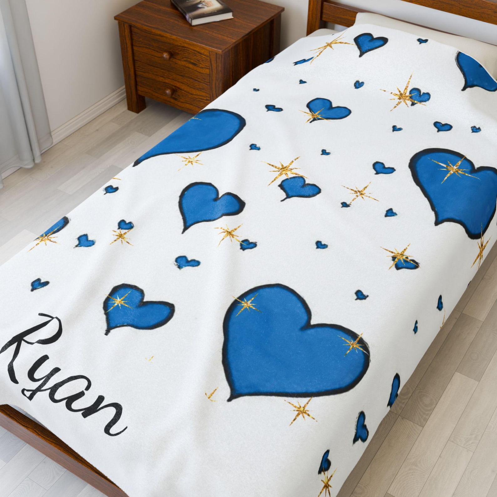 The blanket with blue hearts and the name "Ryan" draped diagonally across a bed in a cozy bedroom