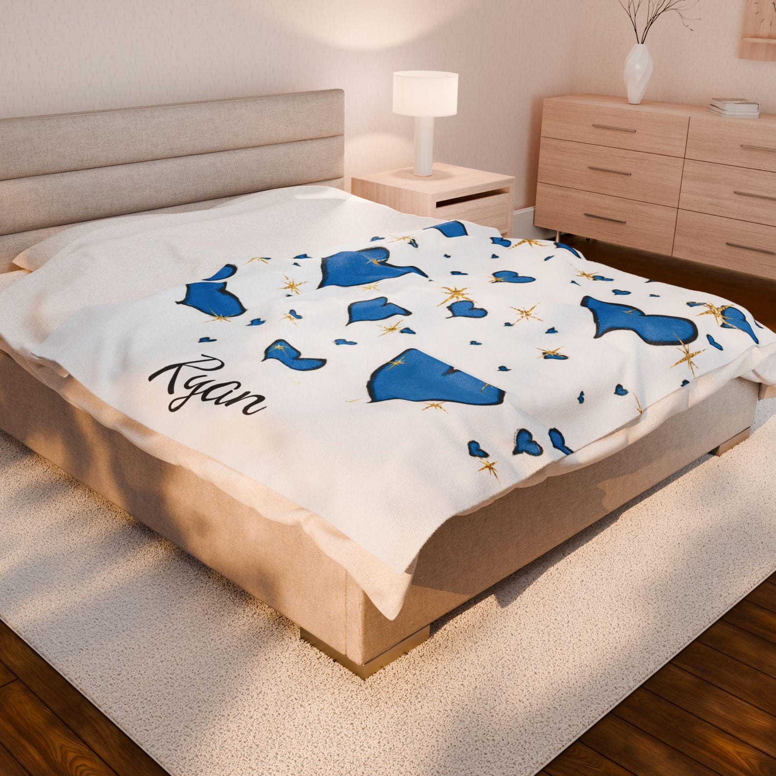 The plush blanket with blue hearts and the name "Ryan" spread out on a large bed