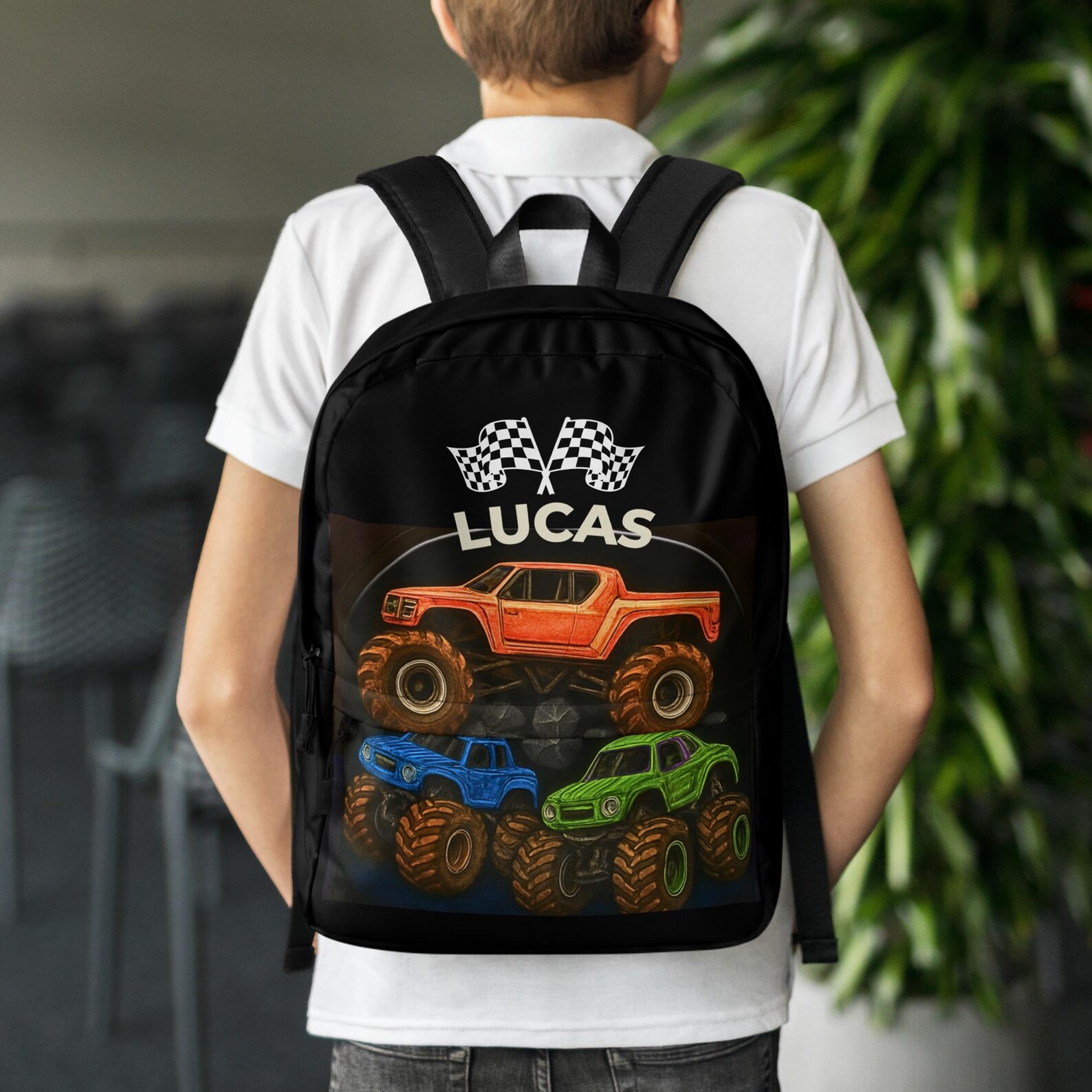 Studio shot of the black backpack printed with three monster trucks and a personalized name