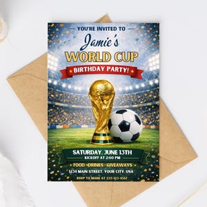 Realistic product mockup displays the World Cup invitation template centered on a dynamic green field background with soccer accents. The editable Canva design features vibrant soccer balls, national flags, bold World Cup typography, and energetic match-day graphics in bright tournament colors. Central customizable text area shows sample wording “World Cup Watch Party