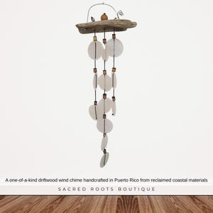 May include: A wind chime featuring a piece of driftwood at the top with a metal wire hanger, small decorative bird figures, and multiple strands of black cord holding circular white shell discs separated by small brown wooden beads.