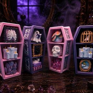 May include: Four coffin-shaped shelves in pink and purple, each featuring three tiers of miniature decorative items including a skeleton rib cage, ghost, skull, candles, crystals, a birdcage, and framed art pieces arranged on a dark wooden surface.
