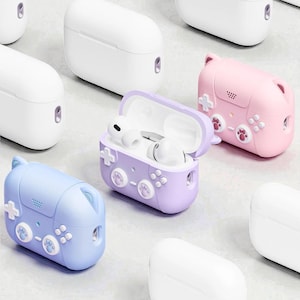 May include: A collection of wireless earbud cases in various colors. The cases are shaped like game controllers, with buttons and directional pads. One case is open, revealing white earbuds. Colors include white, lavender, blue, and pink.