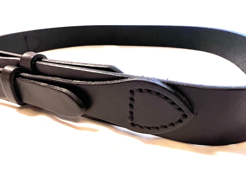 K&ouml;nnte beinhalten: Nahaufnahme eines schwarzen Lederg&uuml;rtels mit einem gen&auml;hten Design. Der G&uuml;rtel besteht aus einem einzigen Lederst&uuml;ck und hat ein klassisches, minimalistisches Design. Die Schnalle ist auf dem Bild nicht zu sehen.