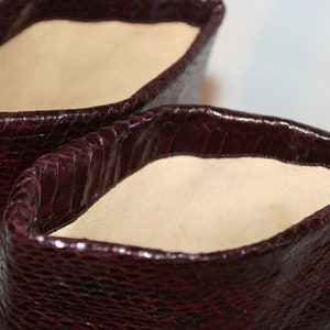 May include: Close-up of the inside of a pair of burgundy leather boots. The boots have a snakeskin pattern and a soft beige lining.
