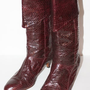 May include: A pair of brown leather boots with a snakeskin pattern. The boots have a low heel and a pointed toe.