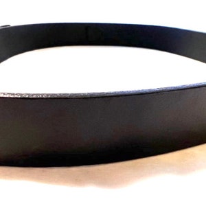 K&ouml;nnte beinhalten: Nahaufnahme eines schwarzen Lederg&uuml;rtels. Der G&uuml;rtel besteht aus einem glatten, dunklen Material und hat ein schlichtes, klassisches Design. Die Schnalle ist auf dem Bild nicht zu sehen. Der G&uuml;rtel ist ein vielseitiges Accessoire.