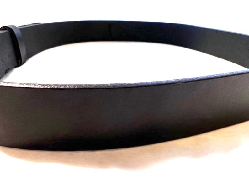 K&ouml;nnte beinhalten: Nahaufnahme eines schwarzen Lederg&uuml;rtels. Der G&uuml;rtel besteht aus einem glatten, dunklen Material und hat ein schlichtes, klassisches Design. Die Schnalle ist auf dem Bild nicht zu sehen. Der G&uuml;rtel ist ein vielseitiges Accessoire.