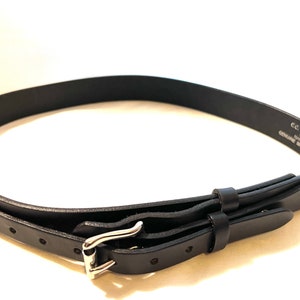 K&ouml;nnte beinhalten: Ein schwarzer Lederg&uuml;rtel mit silberner Schnalle. Der G&uuml;rtel ist aus echtem Zaumleder gefertigt und tr&auml;gt den Aufdruck "C.C. Filson Co. Seattle Made in USA". Der G&uuml;rtel ist etwa 2,5 cm breit.