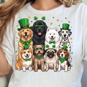 May include: White t-shirt featuring a graphic of nine dogs, each adorned with St. Patrick's Day accessories like green hats, bow ties, and shamrocks. The dogs include a golden retriever, a Newfoundland, a Samoyed, a Dalmatian, a corgi, a pug, and a beagle.